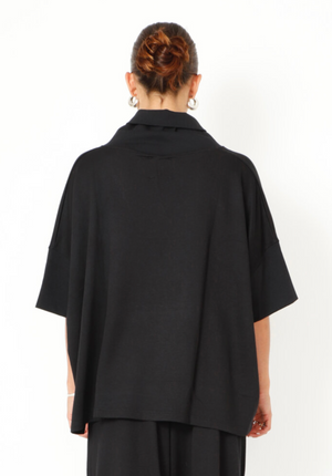 Women's boxy relaxed 1/2 sleeve blouse, with a wide, soft collar, made in a French Terry fabric. In colour black from Sort Aarhus. Back view.