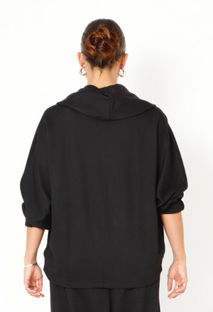 Women's boxy cardigan with a relaxed fit, button closure, and a casual collar. Made in a French Terry fabric. In colour black by Sort Aarhus. Back view.